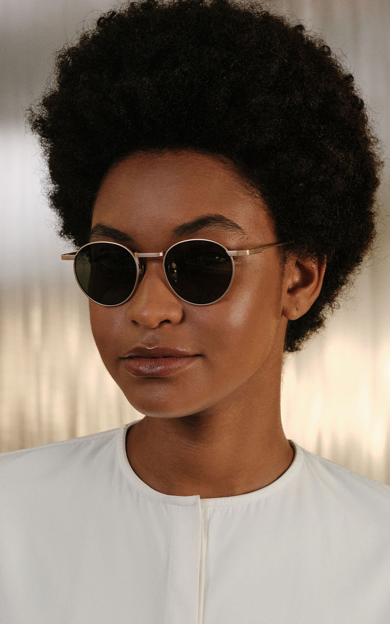 Mulher usando óculos de sol redondos e blusa branca