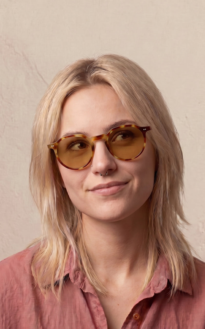 Mulher usando óculos de sol redondos com armação e lentes âmbar 