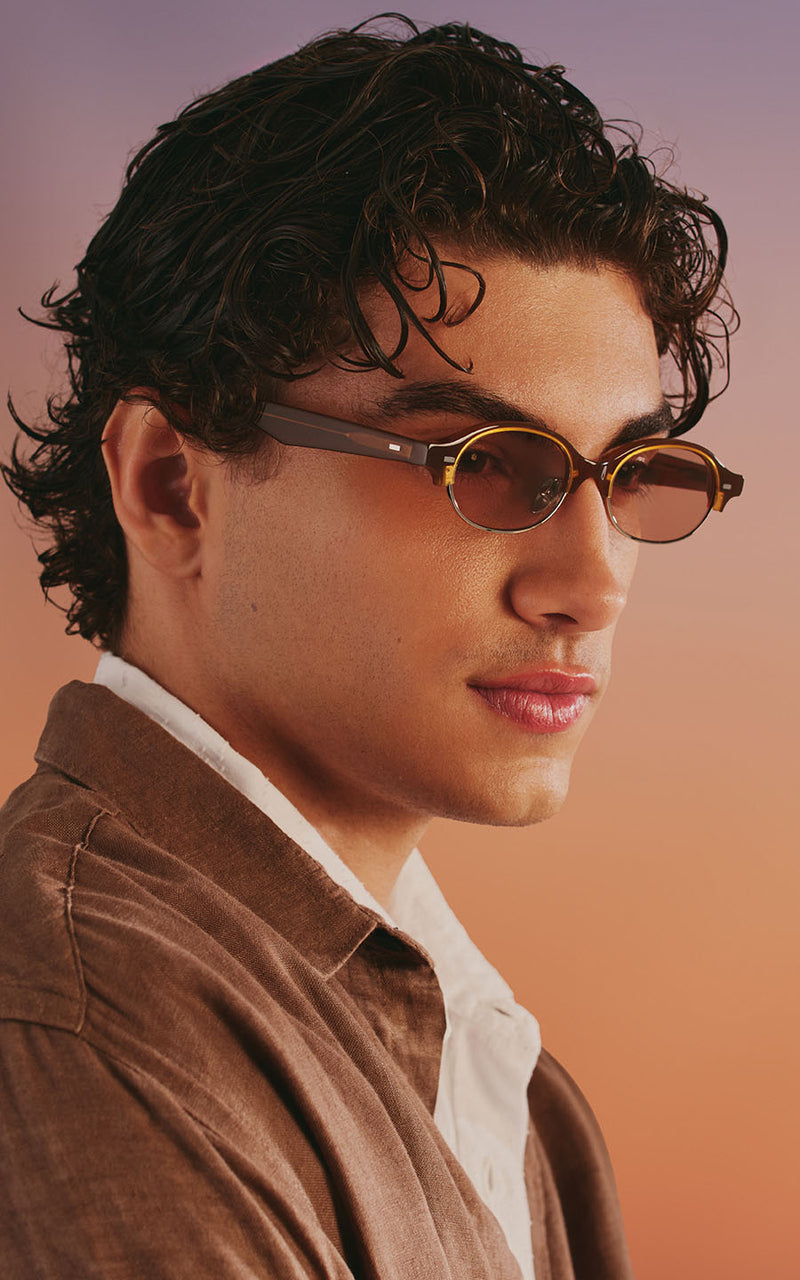 Homem usando óculos de sol com armação oval e lentes coloridas 