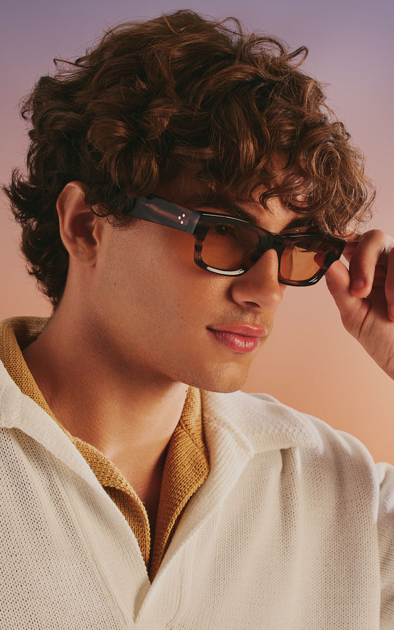 Homem usando óculos de sol com armação escura e lentes âmbar 